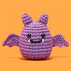 Purple knitted bat toy on an orange background
