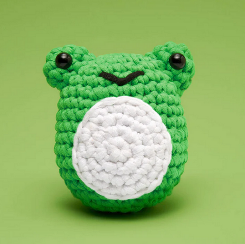 Green crochet frog toy with a white belly