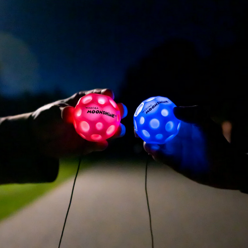 Red and Blue LED moon balls held in hands in dark