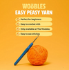 Orange ball of yarn with a blue crochet hook featuring text about 'The Woobles Easy Peasy Yarn'.