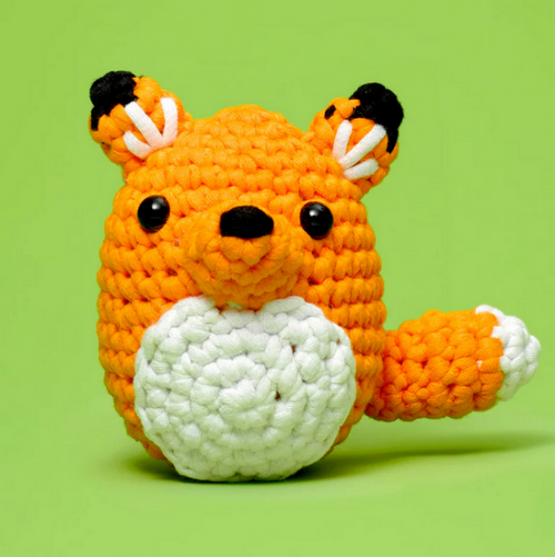 Crocheted fox toy with orange body, white paws, and black ears